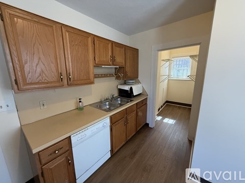 A kitchen with wooden cabinets and a white dishwasher.