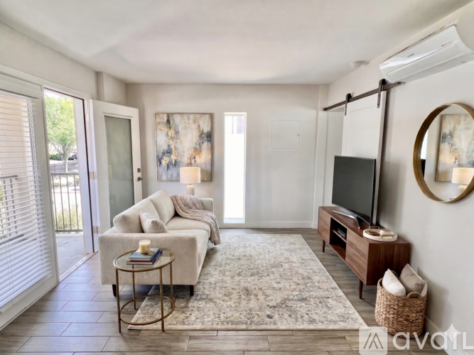 A living room with a sofa, a coffee table, a television, and a rug.