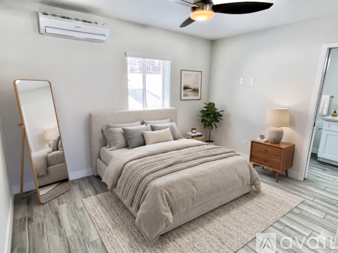 A bedroom with a large bed, a wooden nightstand, and a plant on the windowsill.