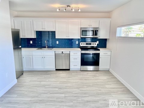 A kitchen with white cabinets and a blue tile backsplash.