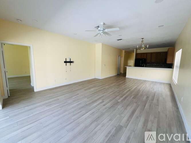 A spacious room with wooden flooring and a ceiling fan.