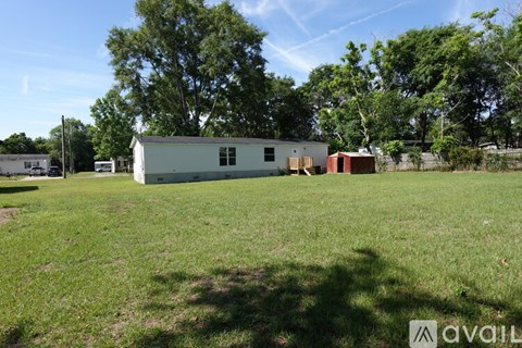 A white building with a red roof is situated in a grassy field.