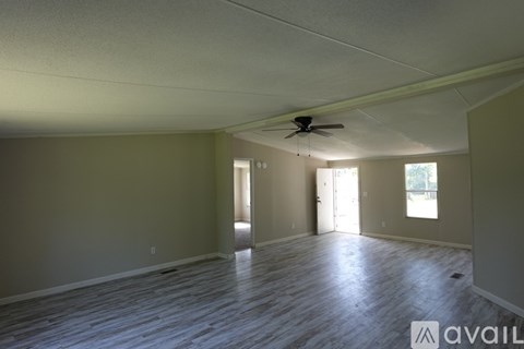 A spacious room with a fan and wooden flooring.