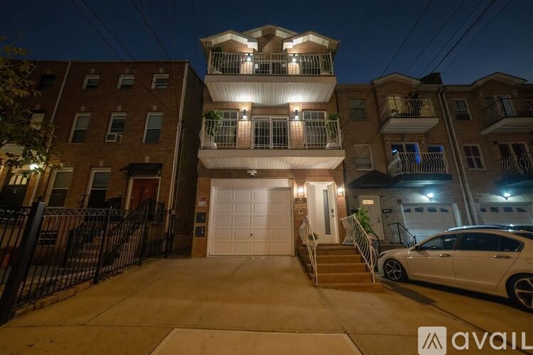 A white car is parked in front of a two-story building at night.
