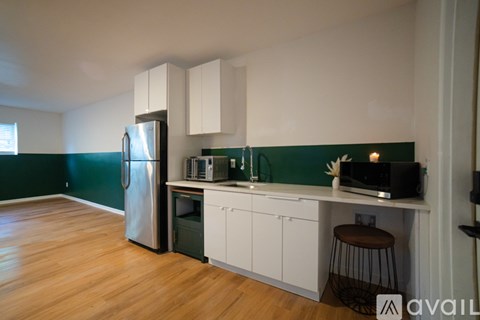 A kitchen with white cabinets and a green backsplash.