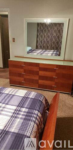 A bedroom with a bed and a wooden dresser.