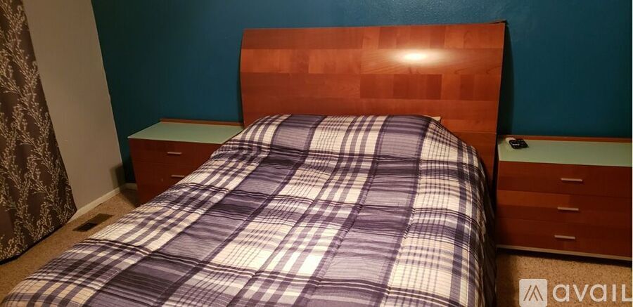 A bed with a plaid comforter and a wooden headboard.