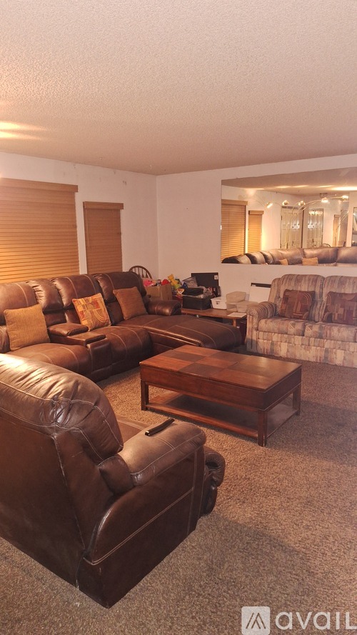 A living room with brown leather furniture and a carpet.