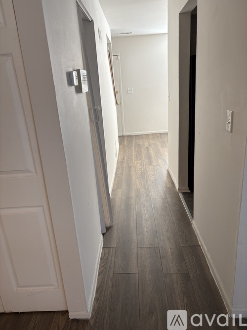 A hallway with a wooden floor and white walls.