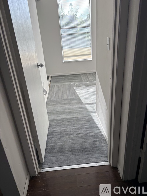A hallway with a carpeted floor and a door on the left.