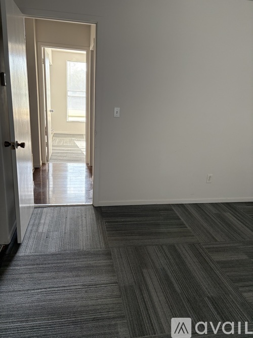 A hallway with a carpeted floor and a door on the left.