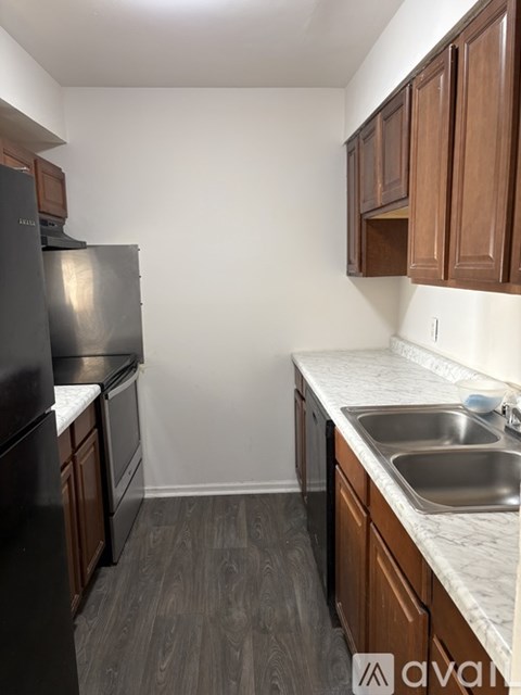 A kitchen with a black fridge and wooden cabinets.