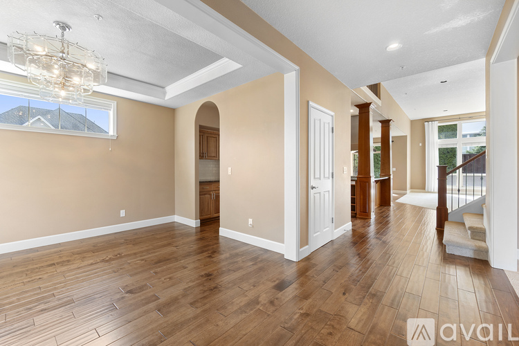 A spacious room with wooden floors and a chandelier.