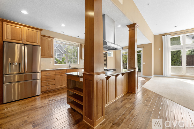 A kitchen with wooden floors and a stainless steel refrigerator.