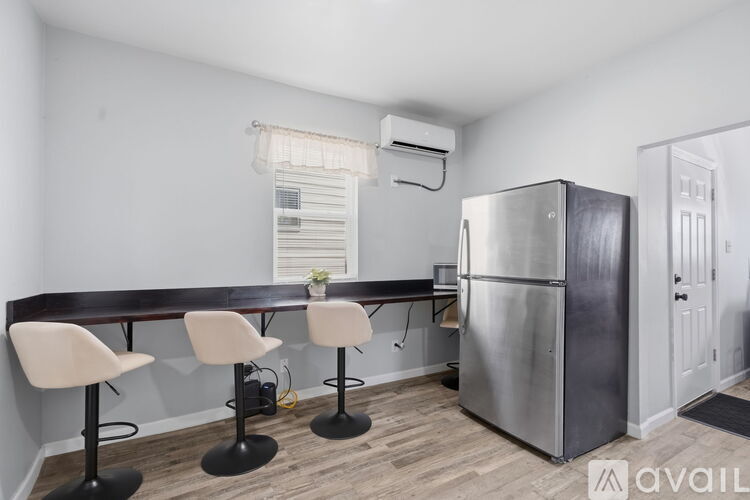 A kitchen area with a bar stool, a table and a fridge.