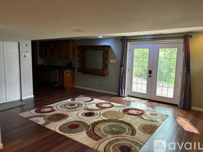 A living room with a rug on the floor and a television on the wall.