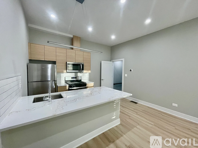 A modern kitchen with a stainless steel refrigerator, microwave, and a white countertop.