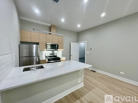 A modern kitchen with a stainless steel refrigerator, microwave, and a white countertop.