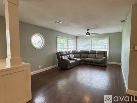 A living room with a large leather sectional sofa and a round window.