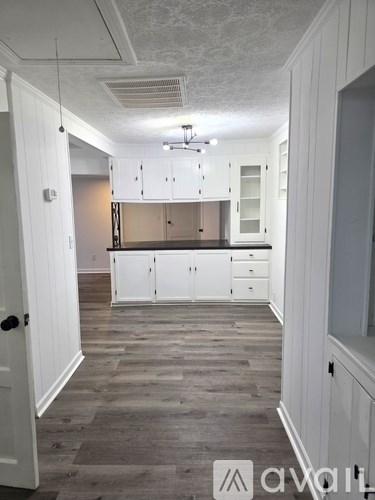 A kitchen with white cabinets and a wooden floor.