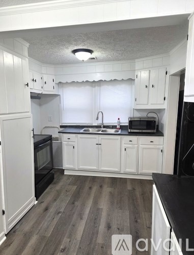 A kitchen with white cabinets and black appliances.
