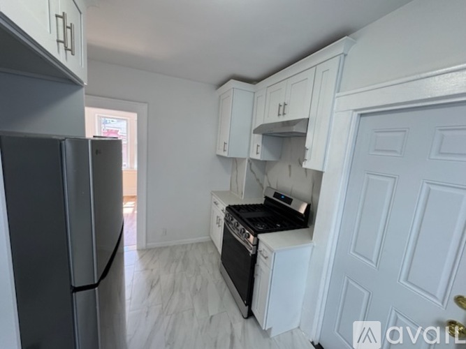 A kitchen with white cabinets and a black fridge.