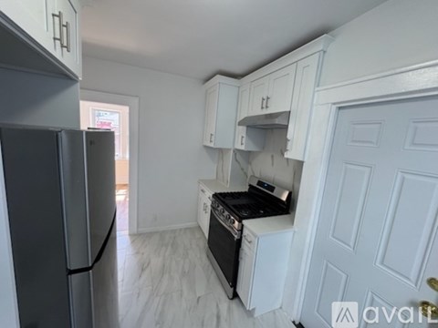 A kitchen with white cabinets and a black fridge.