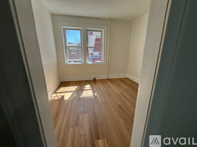 A room with wooden flooring and a window overlooking a street.