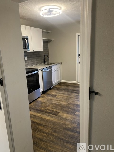 A kitchen with white cabinets and a wooden floor.
