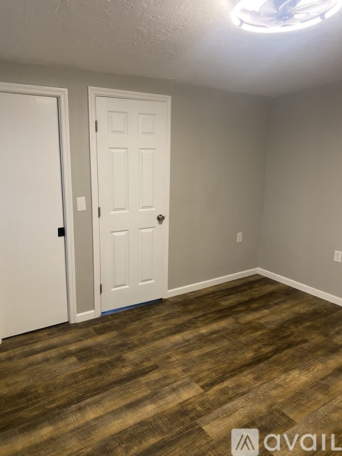 A room with a white door and a wooden floor.