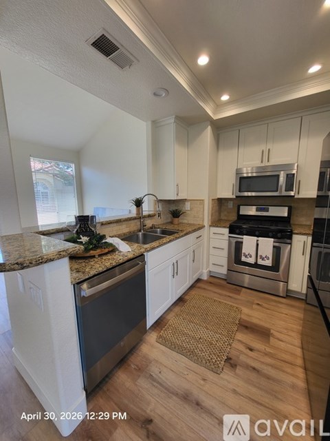 A kitchen with white cabinets and a granite countertop.