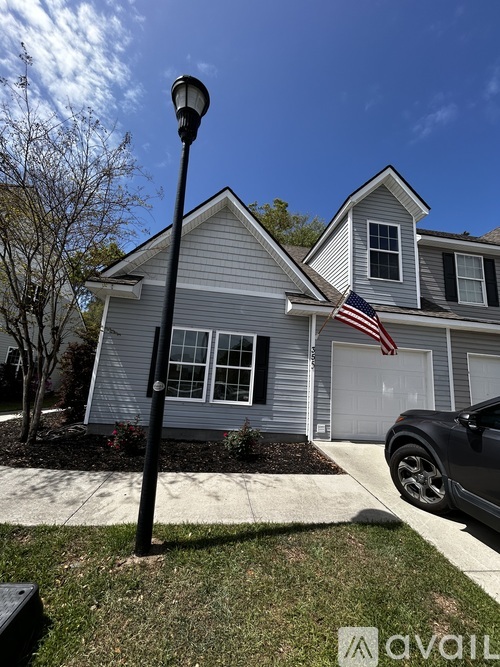 A house with a grey siding and a black car parked in front.