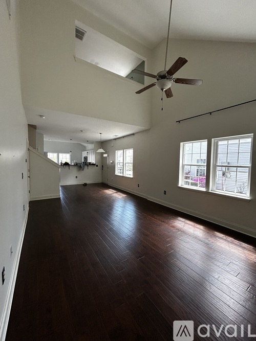 A spacious room with wooden floors and a ceiling fan.