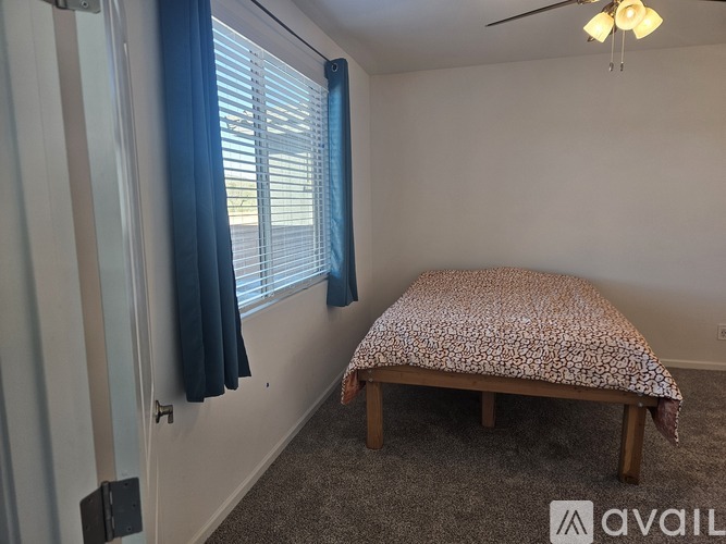 A bedroom with a bed and a window with blue curtains.