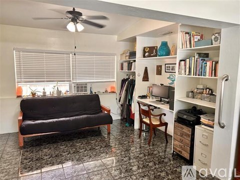 A living room with a black couch and a ceiling fan.