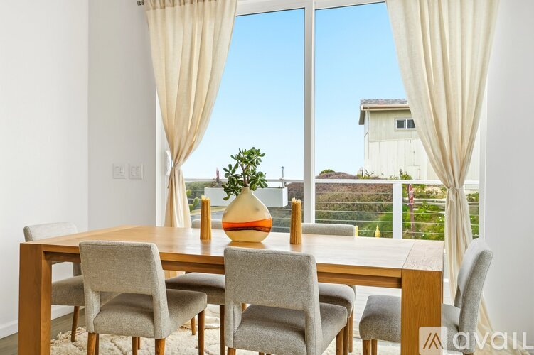 A dining room with a table and chairs with a view of the outside.