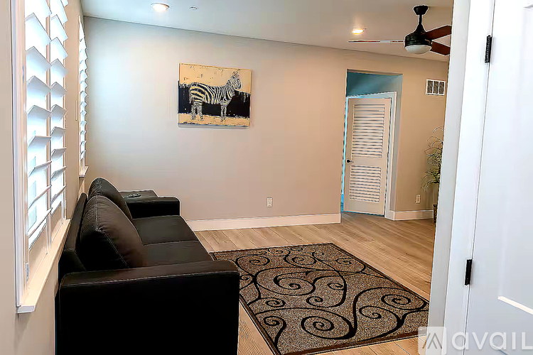 A living room with a black couch and a zebra painting on the wall.