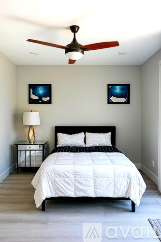 A bedroom with a bed, nightstand, and two pictures on the wall.