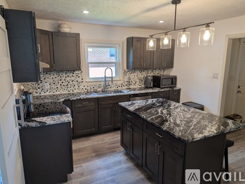 A kitchen with granite countertops and dark cabinets.