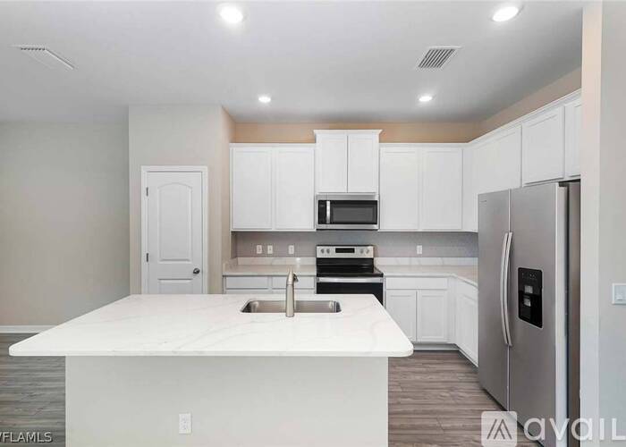 A modern kitchen with white cabinets and stainless steel appliances.
