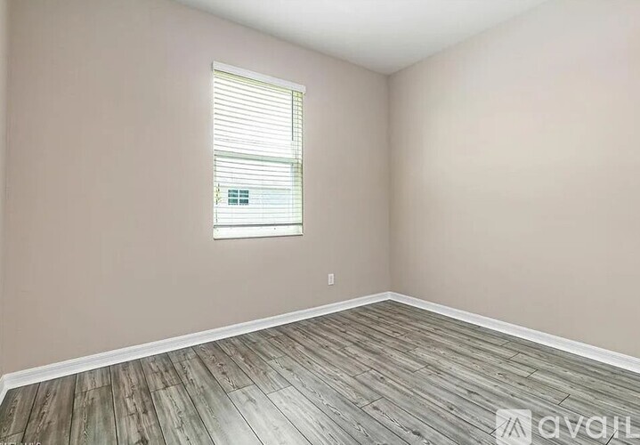 A room with wooden flooring and a window with blinds.