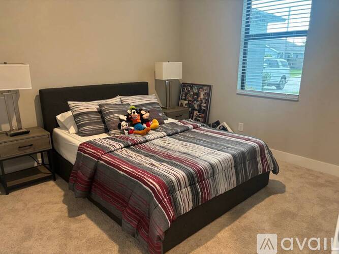 A bedroom with a bed, nightstand, and a window with blinds.