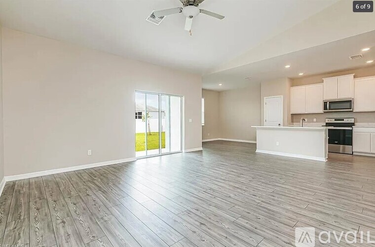 A spacious living room with a sliding glass door leading to a green outdoor area.