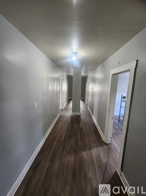 A long hallway with wood floors and white walls.