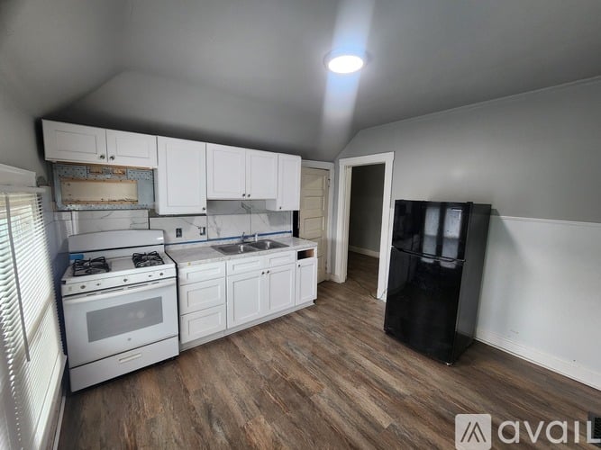 A kitchen with white cabinets and a wooden floor.