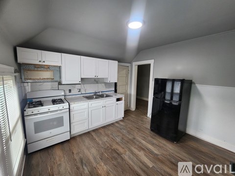 A kitchen with white cabinets and a wooden floor.