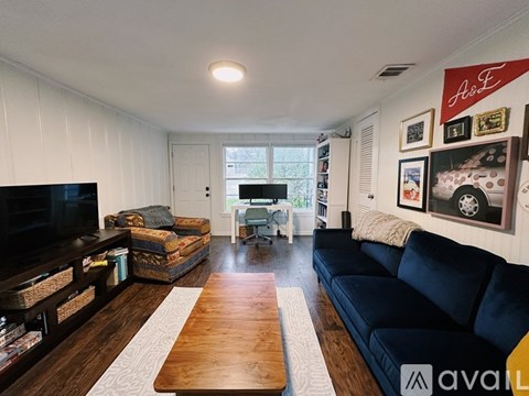 A living room with a black couch and a wooden coffee table.