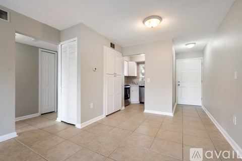 A spacious living room with beige walls and tile flooring.