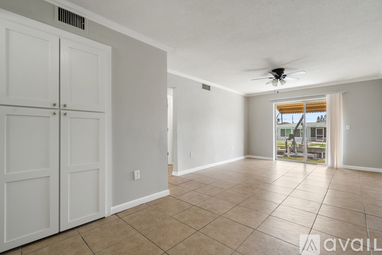 A spacious room with a ceiling fan and sliding glass doors leading to a balcony.