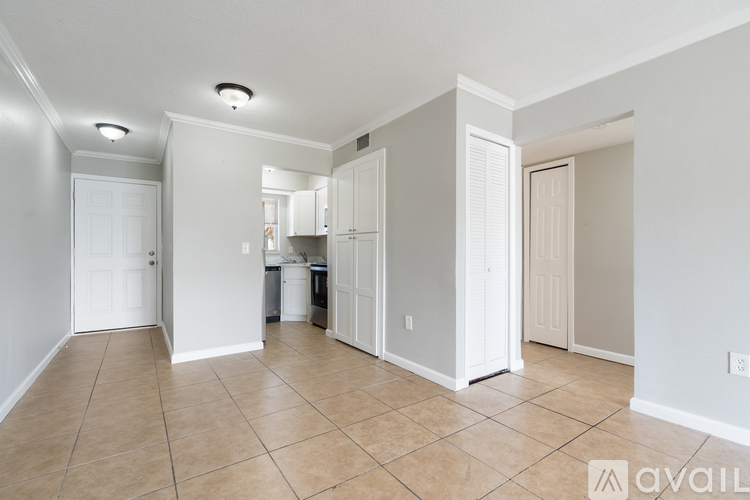 A spacious living room with a kitchen in the background.